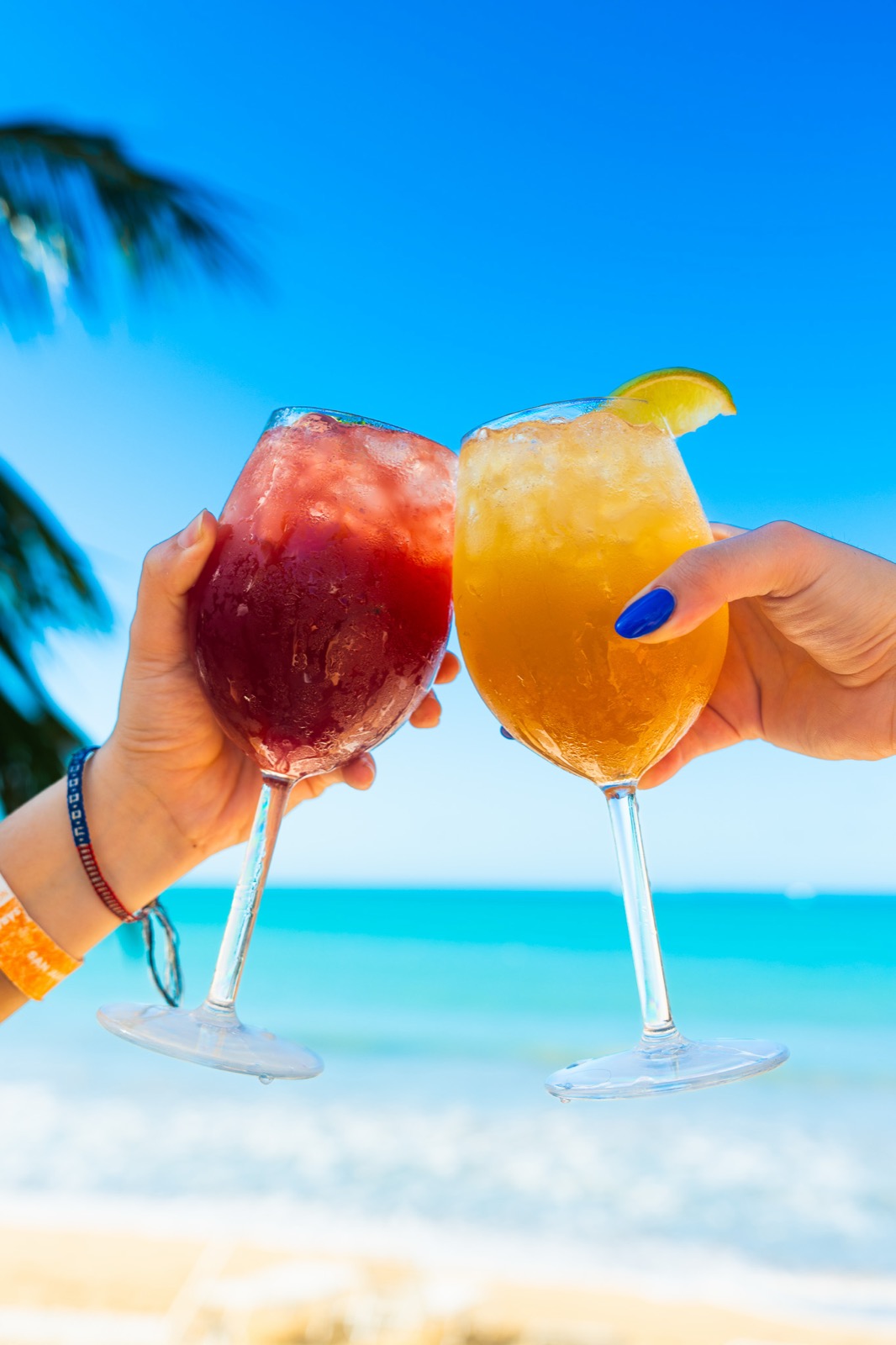 Frozen cocktails held up in front of Isla Verde beach