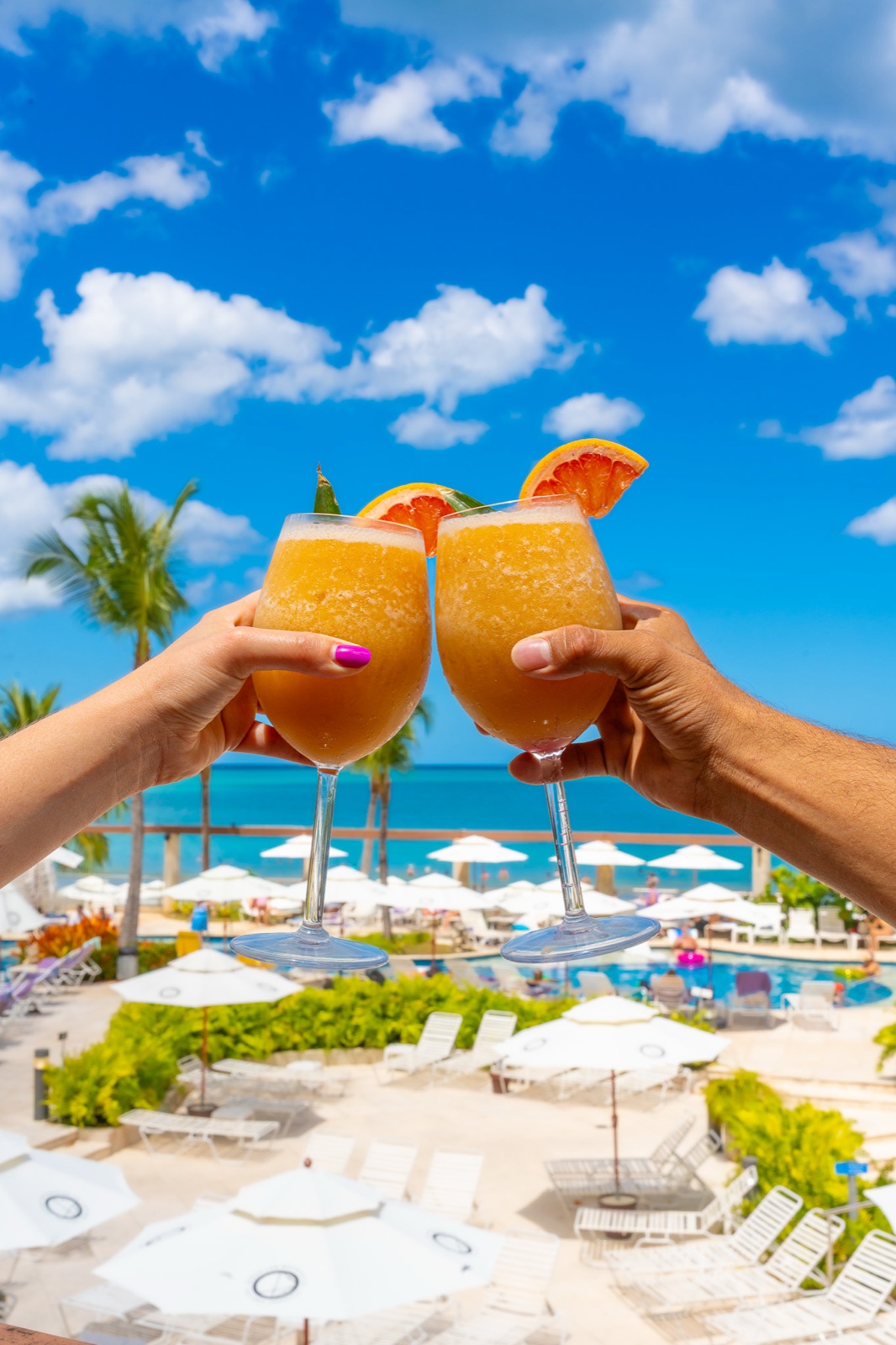 Ocean Lab drinks raised in a toast above the pool at Vivo Beach Club