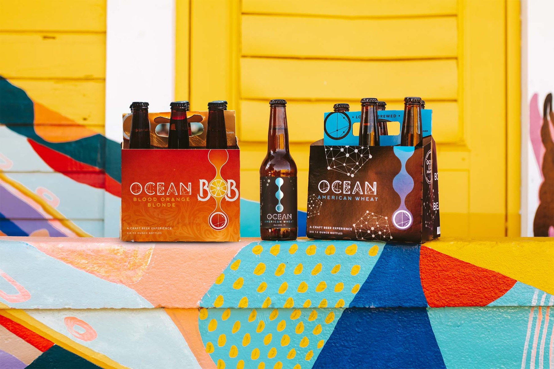 Ocean Lab beer six-packs and bottle displayed against a colorful wall